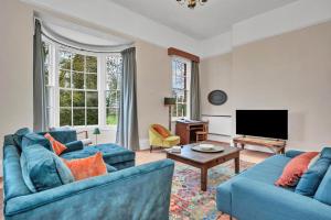 a living room with two blue couches and a tv at Finest Retreats - Clavering Hall in Saffron Walden