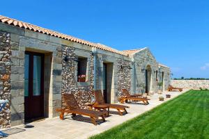 a patio with benches and a stone building at Agriturismo Masseria Quaremme in Carpignano Salentino