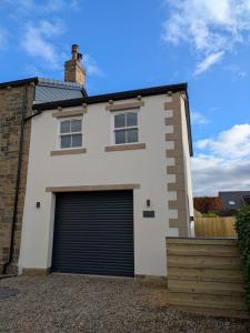 a white house with a garage at Pudsey Loft Apartment in Pudsey