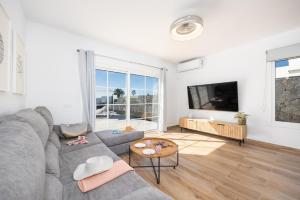 a living room with a gray couch and a flat screen tv at Villa Yaiza Secret 3 in Yaiza