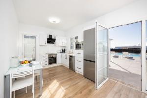 a kitchen with white cabinets and a table with a tablektop at Villa Yaiza Secret 3 in Yaiza