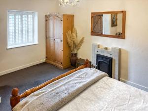 a bedroom with a bed with a fireplace and a mirror at Professors Cottage in Girvan