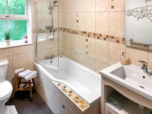 a bathroom with a tub and a toilet and a sink at Professors Cottage in Girvan +2 photos