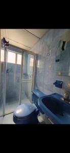 a bathroom with a blue toilet and a tub at Hostel La Casona in Medellín