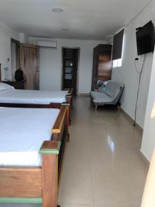a room with four beds and a couch and a television at Rodadero brisas marinas in Gaira