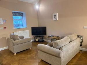 a living room with two couches and a flat screen tv at The Milking Parlour, Wolds Way Holiday Cottages, 1 bed cottage in Cottingham
