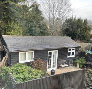 a small black house with a wooden deck at Be Our Guest in Earls Colne