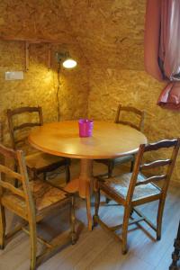 a wooden table with chairs and a purple cup on it at Plantes et sabots in Barriac-les-Bosquets