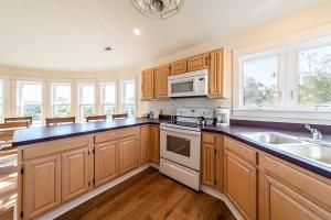 a kitchen with wooden cabinets and a stove top oven at Dolphin's Song -Corolla, Villages at Ocean Hill, 350 Yds to Beach, Pets OK, Hot Tub, Community Pools in Corolla