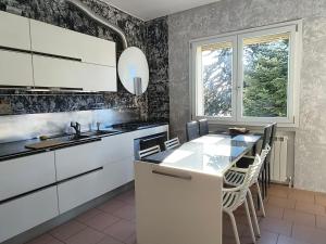 a kitchen with white cabinets and a table with chairs at Family 3-Bedroom Apartment near MXP & Lake Maggiore - Parking in Sesto Calende +22 photos