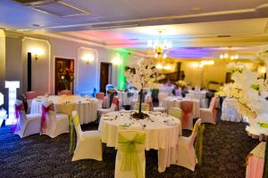 a banquet room with white tables and chairs and flowers at Ty Newydd Country Hotel in Hirwaun