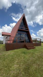 a house with a roof on top of a field at Chalé Pôr do Sol Contenda in Contenda
