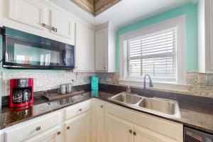 a kitchen with white cabinets and a sink at Paradise Shores 200 in Mexico Beach +15 photos