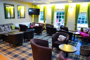 a waiting room with couches and tables and chairs at Ty Newydd Country Hotel in Hirwaun