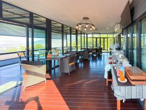 a restaurant with tables and chairs and windows at Laguna Khaokho in Khao Kho