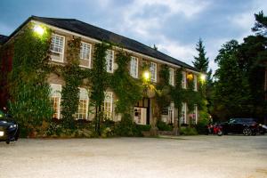 an ivycovered building with a car parked in front of it at Ty Newydd Country Hotel in Hirwaun