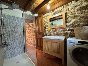a bathroom with a shower and a sink and a washing machine at Cabaña Los Picones in Pisueña +34 photos