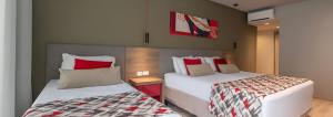a bedroom with two beds with red and white pillows at Laghetto Stilo Borges - Apto 403B in Gramado +20 photos