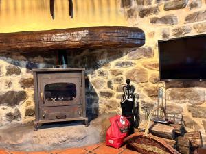 a stone wall with a fireplace and a television at Cabaña Los Picones in Pisueña