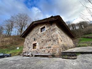 a small stone house sitting on top of a road at Cabaña Los Picones in Pisueña
