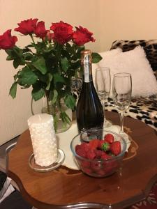 a table with a bottle of wine and a bowl of strawberries at Apartments in Bern - Breitenrainplatz in Bern