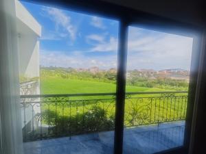 a window view of a green field from a balcony at Santo Guesthouse in Canggu