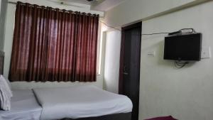 a small bedroom with a bed and a flat screen tv at Hotel Atithi Residency in Lucknow