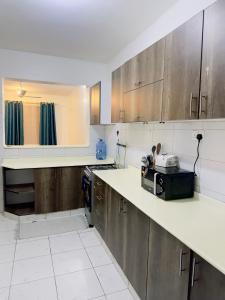 a kitchen with wooden cabinets and a counter top at Diani Beach Modern Apartment in Diani Beach