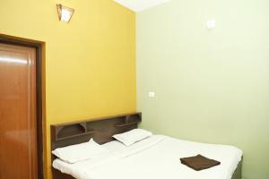 a small bedroom with a bed with white sheets at Clement homes in Kalpetta
