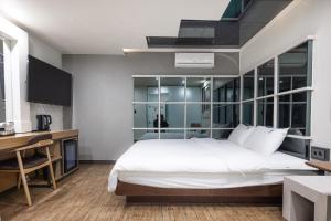 a bedroom with a large white bed and a desk at Lien Hotel Haeundae in Busan