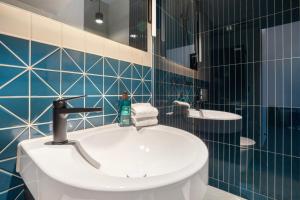 a bathroom with a sink and a toilet and blue tiles at Starlight Loft Lucerne, World Above Chapel Bridge in Lucerne