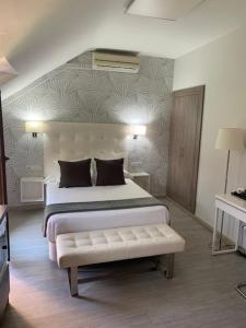 a bedroom with a bed with a bench in it at Hostal el Rocio in Paracuellos de Jarama