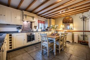 a kitchen with white cabinets and a table with chairs at Smithy Cottage in Hawkshead