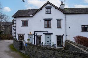 a white house with a stone wall at Smithy Cottage in Hawkshead