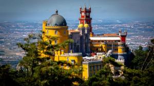 a large yellow building with a clock tower on a mountain at Quarto individual perto de Lisboa e Sintra in Queluz