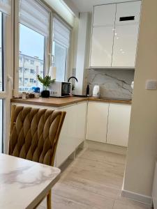 a kitchen with white cabinets and a table and a chair at Leo Apartament in Konin