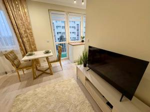 a living room with a flat screen tv and a table at Leo Apartament in Konin