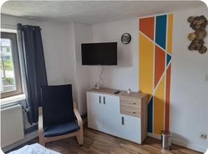 a room with a chair and a tv on a wall at Gästewohnung Rauw in Saint-Vith