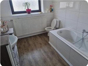 a bathroom with a tub and a toilet and a window at Gästewohnung Rauw in Saint-Vith