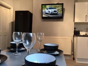 una mesa con copas de vino y un coche en la TV en Samuel Place by SG Property Group, en Crewe