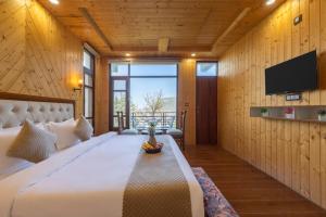 a bedroom with a large bed and a flat screen tv at Evening Sky Hotel - Kasauli !!! in Kasauli