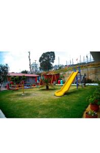 a playground with a yellow slide in the grass at Paradise Perfect - Nonsmoking Non alcoholic No unmarried couples in Ooty
