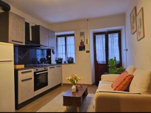a living room with a couch and a kitchen at Alpine View Varzo - Train Station in Varzo