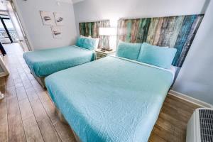 two beds in a small room with blue sheets at Prime Ocean Frontage The Pavilion in Myrtle Beach
