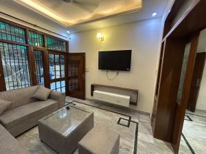 a living room with a couch and a tv on a wall at Serene Stay 22 in Chandīgarh