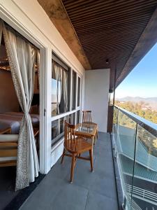 a room with a balcony with a table and a bed at The Grand Dwaper A- Luxury Rooms & Parking Walking Distance From Mall Road in Mussoorie