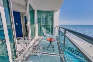 a balcony with chairs and a table and the ocean at Amazing Oceanfront 2BR condo with pools and views in Myrtle Beach