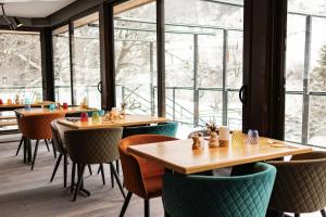 a restaurant with tables and chairs and large windows at Hôtel Le P'tit Cham, au pied du Sancy in Le Mont-Dore