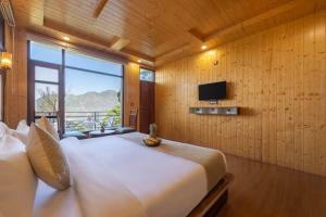 a bedroom with a large white bed and a television at Evening Sky Hotel - Kasauli !!! in Kasauli +17 photos