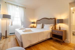 a bedroom with a large white bed with two lamps at Boutique Hotel Casa da Brêa Viana do Castelo in Viana do Castelo +28 photos